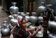 首都ダッカの路上で水をくむ女性。バングラデシュ政府は、７％台の成長を目指す（ＡＰ）