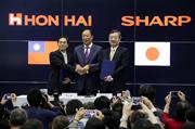シャープの高橋興三社長（右）、鴻海精密工業の戴正呉副総裁（左）と手を組む鴻海の郭台銘会長＝４月２日、堺市