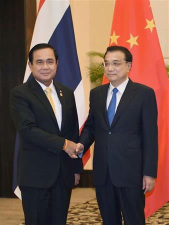 中国の李克強首相（右）と握手するタイのプラユット暫定首相＝３月２３日、中国海南省（タイ首相府提供・共同）