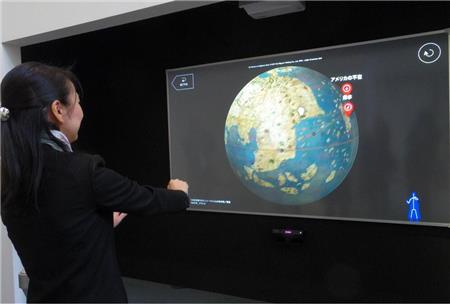 手を振って映像の地球儀を操作する展示