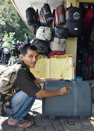 インドネシアの首都ジャカルタのスラバヤ通りで、中古スーツケースを磨くムハンマド・ユスフさん＝４月１日（共同）
