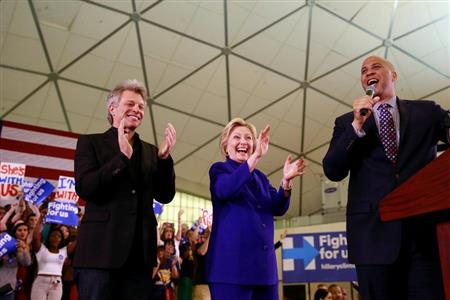 有名司会者のコーリー・ブッカー氏（右）に紹介される米民主党候補のヒラリー・クリントン前国務長官（中央）とロック歌手のジョン・ボンジョビ氏＝１日、ニューアークのラトガース大学ニューアーク校（ロイター）