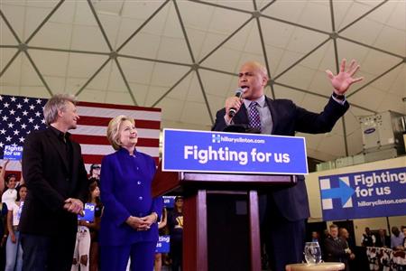 米民主党の大統領候補、ヒラリー・クリントン前国務長官（中央）とロック歌手のジョン・ボンジョビ氏（左）を紹介する司会者のコーリー・ブッカー上院議員＝１日、米ニューアークのラトガース大学ニューアーク校（ロイター）