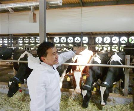 壁一面に換気扇が設置された牛舎を紹介するパナソニック環境エンジニアリングの担当者＝３日、栃木県大田原市