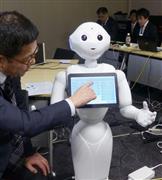 受け付け役のロボットに症状などの情報を入力する患者役の自治医大担当者＝３月２８日、東京都千代田区