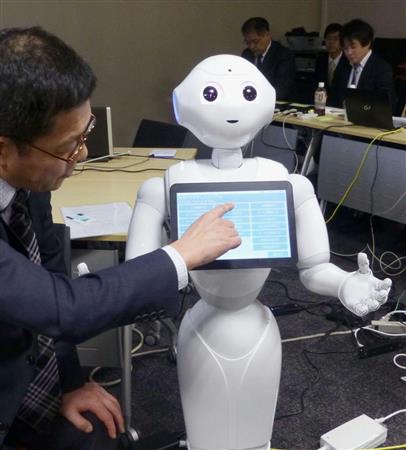 受け付け役のロボットに症状などの情報を入力する患者役の自治医大担当者＝３月２８日、東京都千代田区