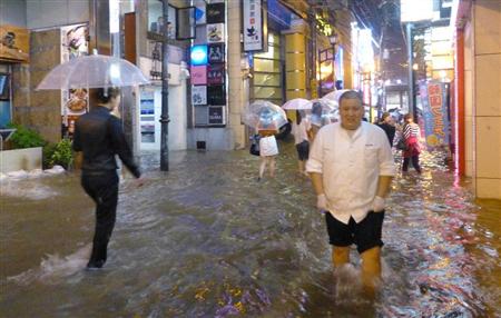 冠水した繁華街の道路を歩く男性ら＝２０日夜、長崎市