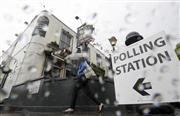 雨の中、傘を差して国民投票の投票所へ向かう女性＝２３日、ロンドン（ロイター）