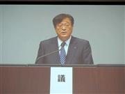 三菱自動車の株主総会で話す益子修会長を映したモニター画面より＝２４日、千葉市美浜区中瀬の幕張メッセ（会田聡撮影）