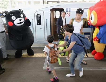 九州新幹線の運行本数が通常に戻り、ホームでくまモンに迎えられる乗客＝４日午前、ＪＲ熊本駅