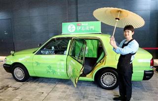 番傘で出迎える「伊右衛門」のラッピングをしたおもてなしタクシーの運転手＝５日、東京都千代田区
