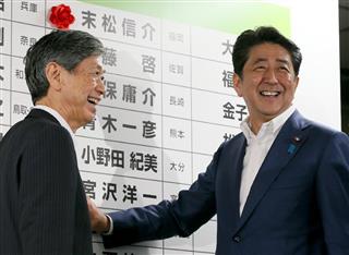 当選確実となった候補者にバラをつける自民党総裁の安倍晋三首相（右）と高村正彦副総裁＝１０日午後、東京・永田町の自民党本部（桐原正道撮影）