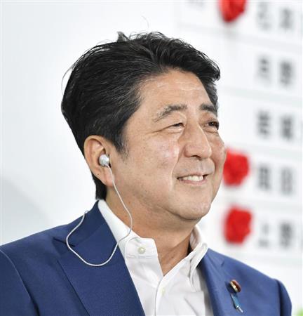 自民党の開票センターでテレビ局のインタビュー中に笑顔を見せる安倍首相＝１０日午後１０時２１分、東京・永田町の党本部
