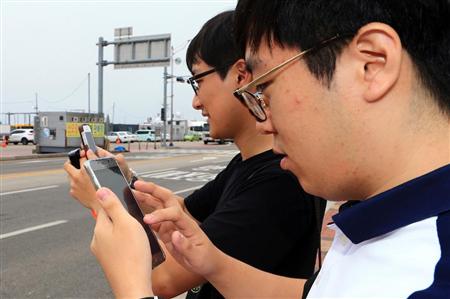 路上で「ポケモンＧＯ」をプレイする韓国の若者＝１３日、束草（ＡＰ）