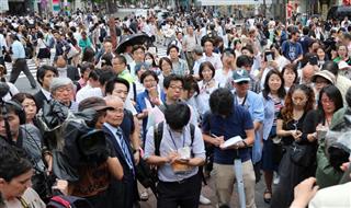 東京・渋谷のハチ公前で、東京都知事選挙候補者の演説を聞く有権者ら＝１４日午後
