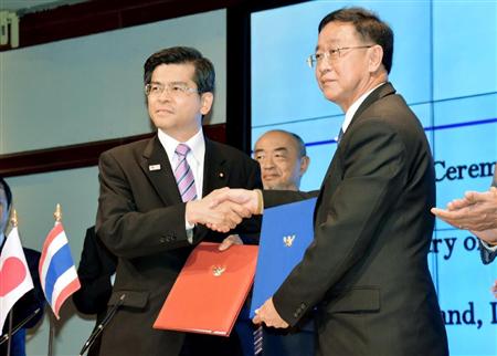 鉄道協力に関する覚書に署名後、握手する石井国交相（左）とタイのアーコム運輸相＝６日、バンコク（共同）