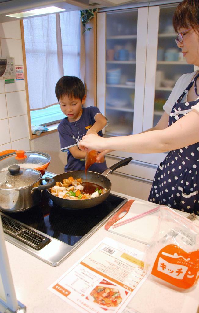 酢豚の調理を手伝う男子児童＝さいたま市