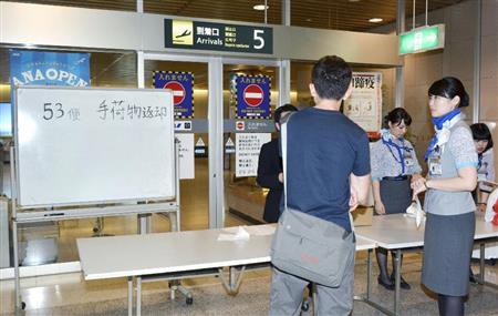 羽田空港で搭乗した全日空の便に手荷物が積み込まれず、後続便が運搬する荷物を待つ乗客（手前）＝１２日午後、新千歳空港
