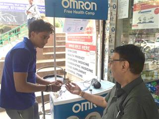 インド・グルガオンで、オムロンヘルスケアの現地法人が開いた無料測定会に参加して血糖値を測る男性（右）＝６月（共同）
