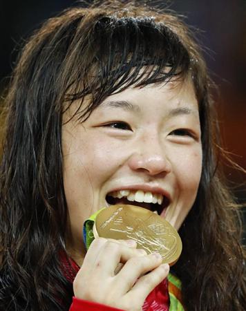 女子４８キロ級で獲得した金メダルを口に運ぶ登坂絵莉＝リオデジャネイロ（共同）