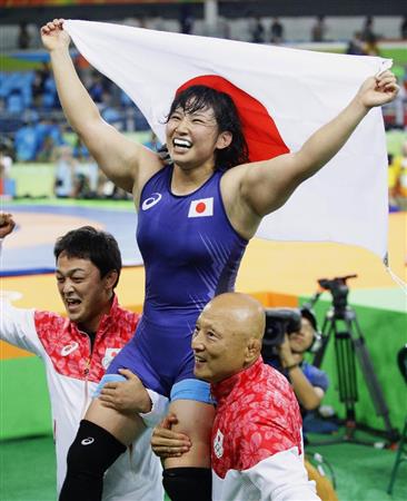 女子６９キロ級で優勝し、日の丸を掲げ笑顔の土性沙羅。右下は栄和人チームリーダー＝リオデジャネイロ（共同）