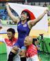 女子６９キロ級で優勝し、日の丸を掲げ笑顔の土性沙羅。右下は栄和人チームリーダー＝リオデジャネイロ（共同）