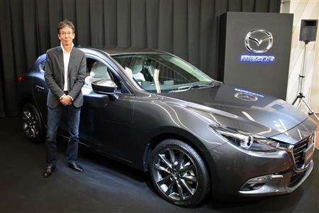 マシーングレーに塗られた新型アクセラと、マツダのカラーデザイナー、岡本圭一氏