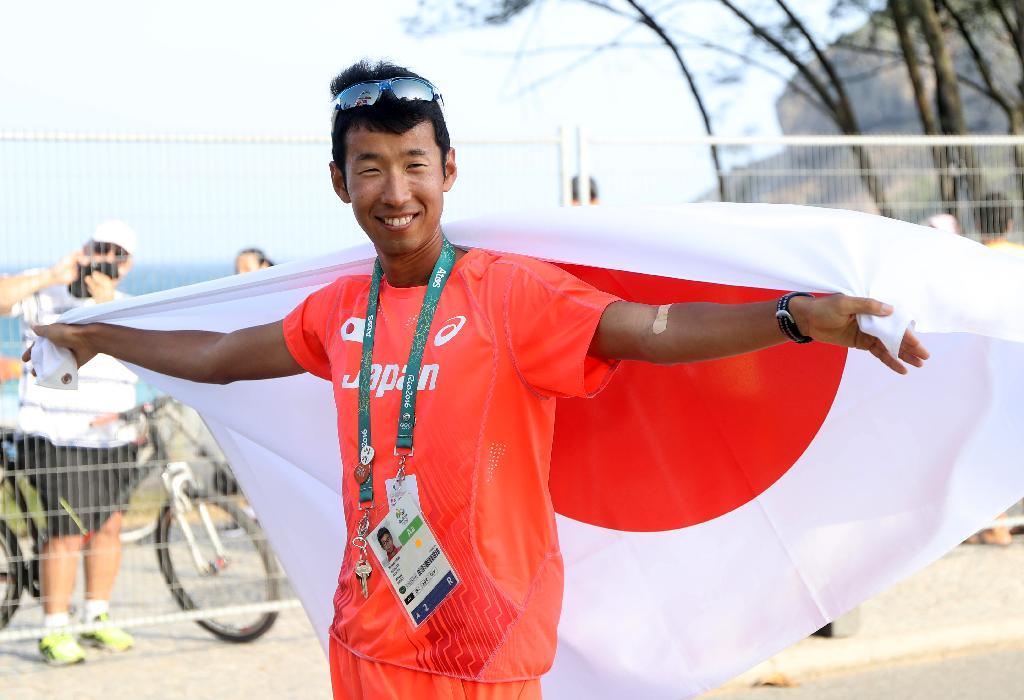 陸上競技５０キロ競歩決勝３位でフィニシュするも失格扱いとされ、審議の結果再度３位となり再び国旗を掲げた荒井広宙＝１９日、ポンタル周回コース（撮影・桐山弘太）