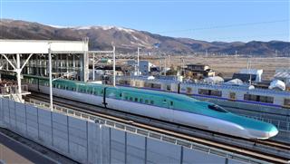 朝日を浴びながら東京へ向け新函館北斗駅を出発した北海道新幹線＝２６日午前、北海道北斗市（三尾郁恵撮影）