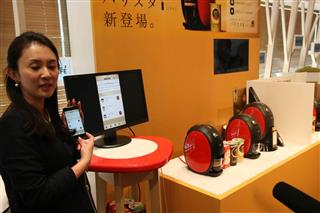 専用のアプリを入れたスマートフォンを操作し、新型コーヒーマシンと連動させる実演を行う担当者＝２６日、東京都渋谷区（永田岳彦撮影）