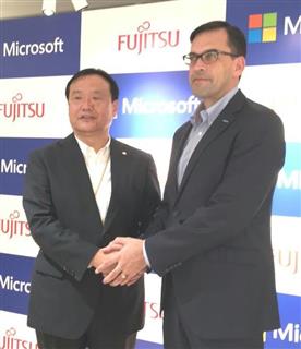 記者会見後に握手する富士通の阪井洋之執行役常務（左）と日本マイクロソフトの平野拓也社長＝１日、東京都港区