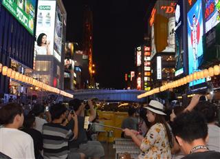 道頓堀川を航行するクルーズ船上で、「グリコの看板」などを夢中で撮影する韓国人客ら＝８月１８日午後７時すぎ、大阪市中央区
