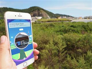 東日本大震災による津波で流失した映画館「岡田劇場」があった場所。「ポケモンＧＯ」のゲーム画面では流失前の姿が再現され、ゲームの拠点に設定されている＝宮城県石巻市（高橋寛次撮影、現地で撮影した画面を合成）