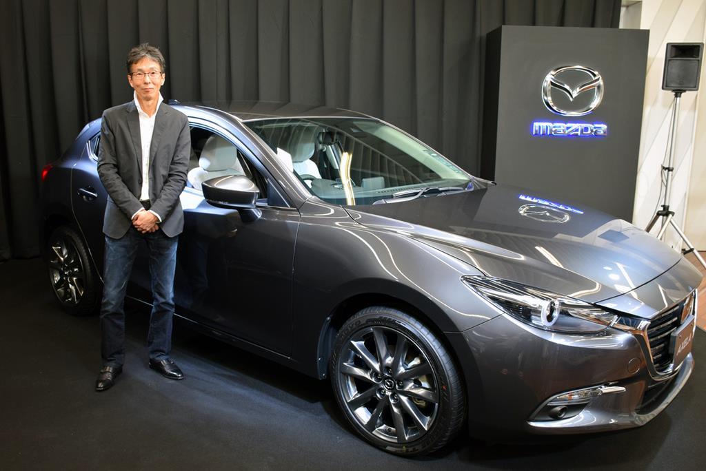 マツダのカラーデザイナー・岡本圭一氏と、マシーングレーに塗装されたアクセラ