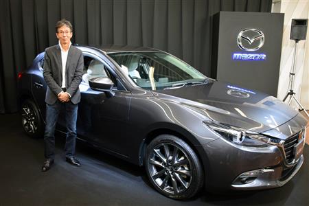 マツダのカラーデザイナー・岡本圭一氏と、マシーングレーに塗装されたアクセラ