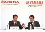 渡部克明ヤマハ取締役常務執行役員（右）からマイクを受け取る青山真二ホンダ取締役執行役員（左）＝５日午後、東京都港区芝公園の芝パークホテル（鈴木健児撮影）