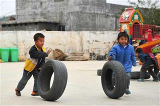 タイヤを転がして遊ぶ少数民族ヤオ族の子供たち。中国では廃タイヤの再利用は進んでおらず、放置タイヤの火災もたびたび発生している＝広西チワン族自治区河池市大化ヤオ族自治県（中国新聞社）