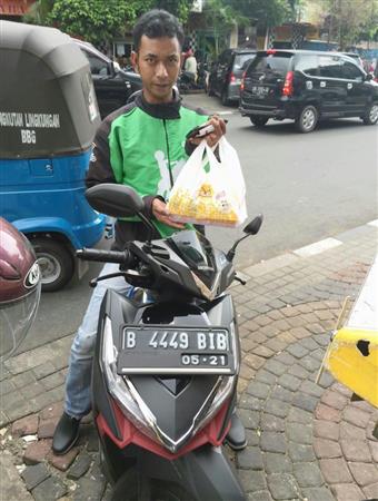 顧客の注文を受けたランチボックスを手にする「ゴジェック」の運転手＝８月、ジャカルタ（共同）