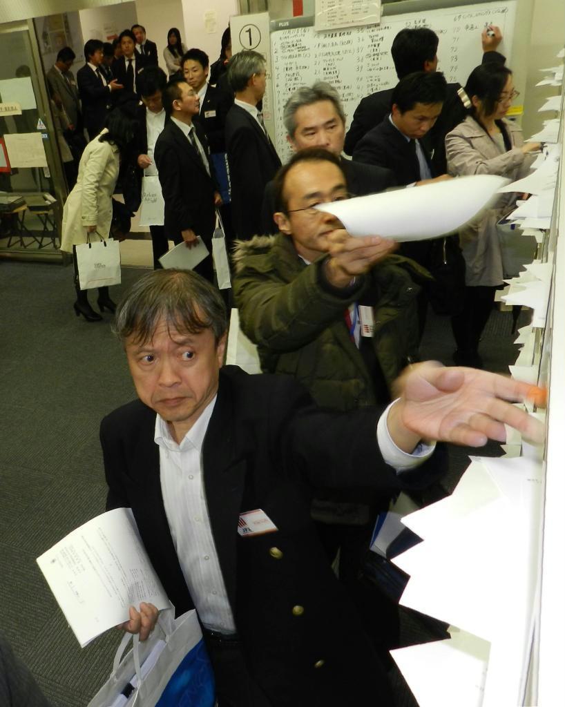 決算資料を次々と棚に投函する企業の担当者＝１１日、東京証券取引所