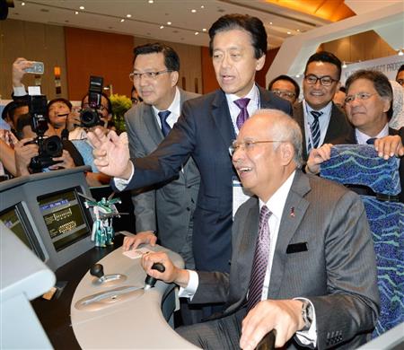 高速鉄道のシミュレーターを操作するマレーシアのナジブ首相（手前）。ＪＲ東日本の小県方樹副会長（その後ろ）＝１０月１７日、クアラルンプール（共同）