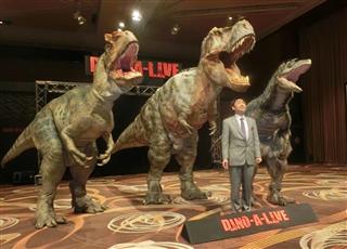 生きているかのように歩き回るリアルな恐竜の着ぐるみと金丸賀也社長=東京都港区 生きているかのように歩き回るリアルな恐竜の着ぐるみと金丸賀也社長=東京都港区