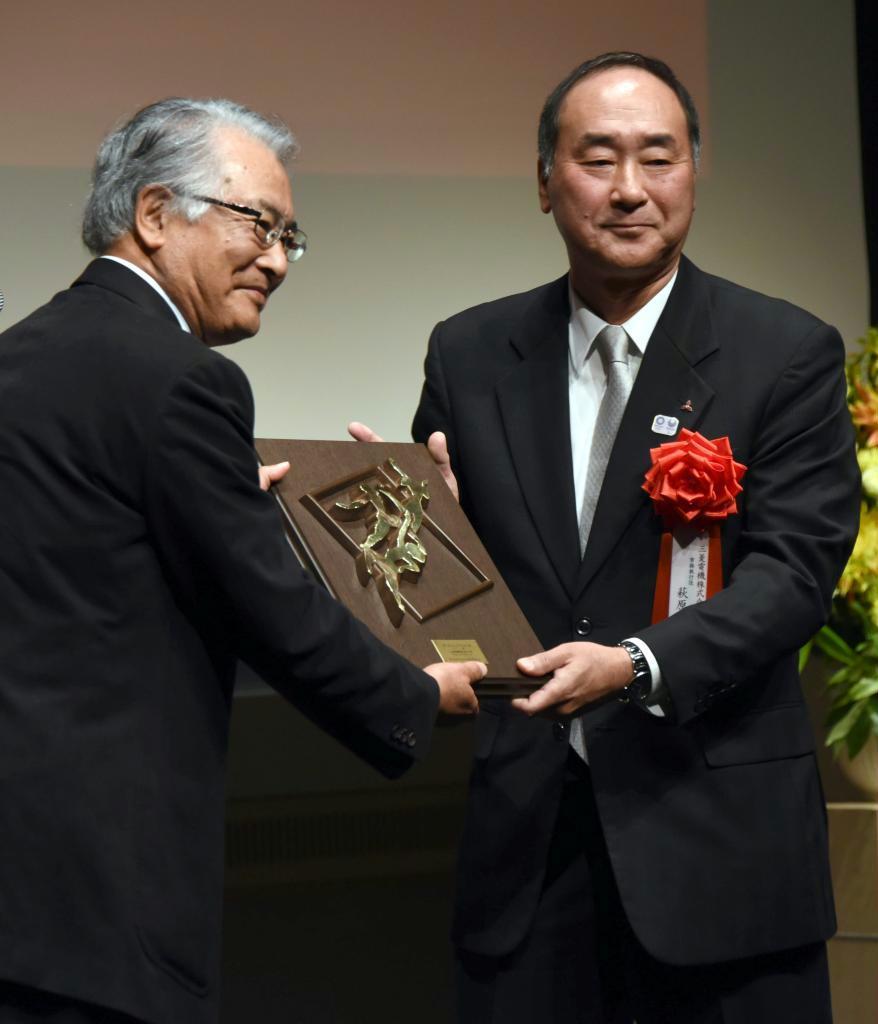 大賞を受賞し、須藤春夫審査委員長（左）から盾を贈られる三菱電機の萩原稔常務執行役＝２５日、東京・大手町