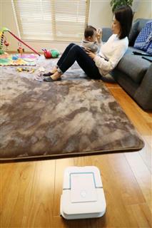 子供をあやしながら床拭きロボットに掃除を任せる高橋みずきさん＝東京都内