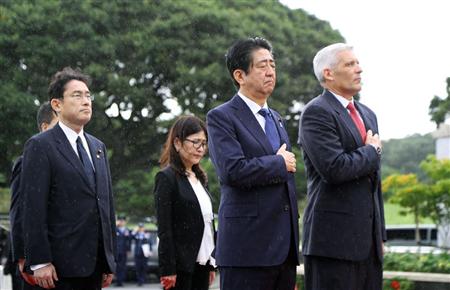 雨の中、米国立太平洋記念墓地で胸に手を当てる安倍首相（右から２人目）ら＝２６日、米ハワイ・ホノルル（代表撮影・共同）