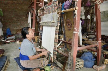 カトマンズ郊外のジャワラケル手工芸センターの仮工場で、チベットじゅうたんを織る女性（共同）