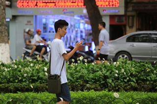 首都ハノイの街中で携帯端末を操作しながら歩く男性。ベトナムは携帯を使った電子決済が急増している（ＡＰ）