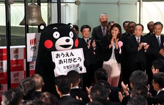 東証大納会で登壇し、被災地支援に対してのメッセージを掲げる熊本県ＰＲマスコットのくまモンとレスリングの伊調馨選手 ＝３０日午後、東京都中央区の東京証券取引所（川口良介撮影）