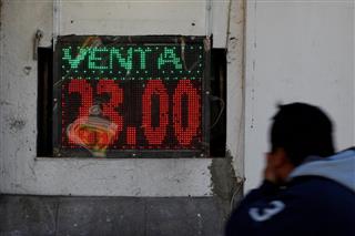 メキシコ・ペソと米ドルの交換レートを示すボードを見て思わず口を押さえる男性=メキシコのシウダーフアレス(ロイター) メキシコ・ペソと米ドルの交換レートを示すボードを見て思わず口を押さえる男性=メキシコのシウダーフアレス(ロイター)