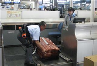 サイバーダインのロボスーツを身につけて、重いスーツケースを動かす航空会社の従業員＝２４日、千葉県成田市の成田空港