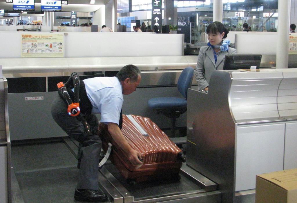 サイバーダインのロボスーツを身につけて、重いスーツケースを動かす航空会社の従業員＝２４日、千葉県成田市の成田空港